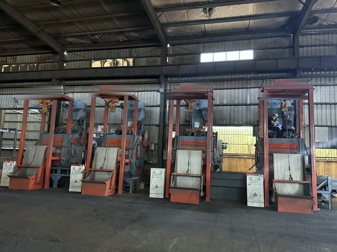 Row of tumble-belt shot blasting machines cleaning castings